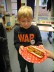 Ein Schüler präsentiert auf einem Teller einen selbstgemachten Hot Dog.
