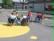 Das Bild zeigt eine Gruppe von Kindern die auf dem Schulhof in ihren Rollstuhlen miteinander spielen.